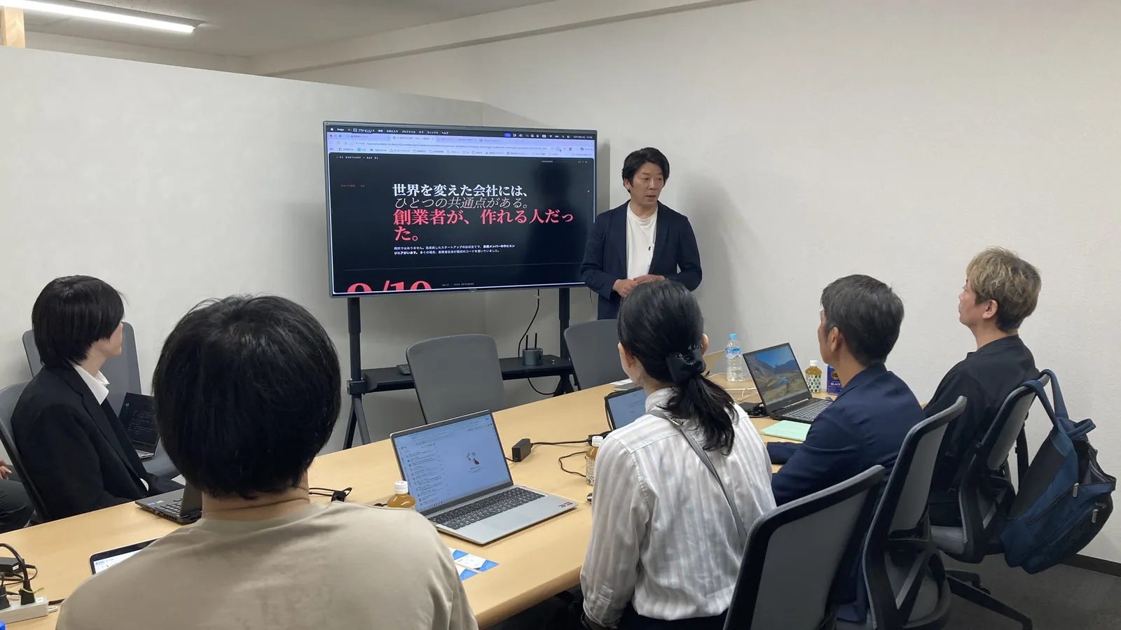 研修の様子。講師がモニターの前で話し、受講者がノートPCを前に聞いている