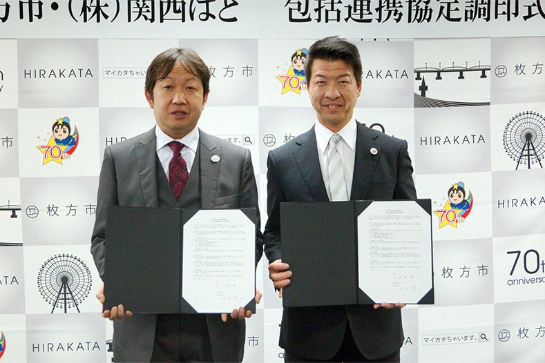 枚方市・株式会社関西ぱど 包括連携協定調印式。協定書を手に並ぶ2人(左から北田代表取締役、伏見枚方市長)