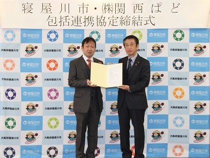 寝屋川市・株式会社関西ぱど 包括連携協定締結式。協定書を手に並ぶ2人