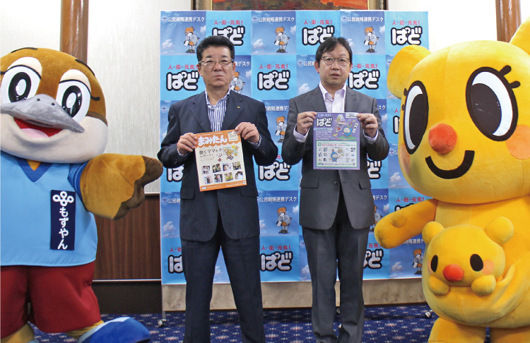 大阪府との包括連携協定の記念撮影。『まみたん』と『ぱど』を手に並ぶ2人と、大阪府のPRキャラクター「もずやん」