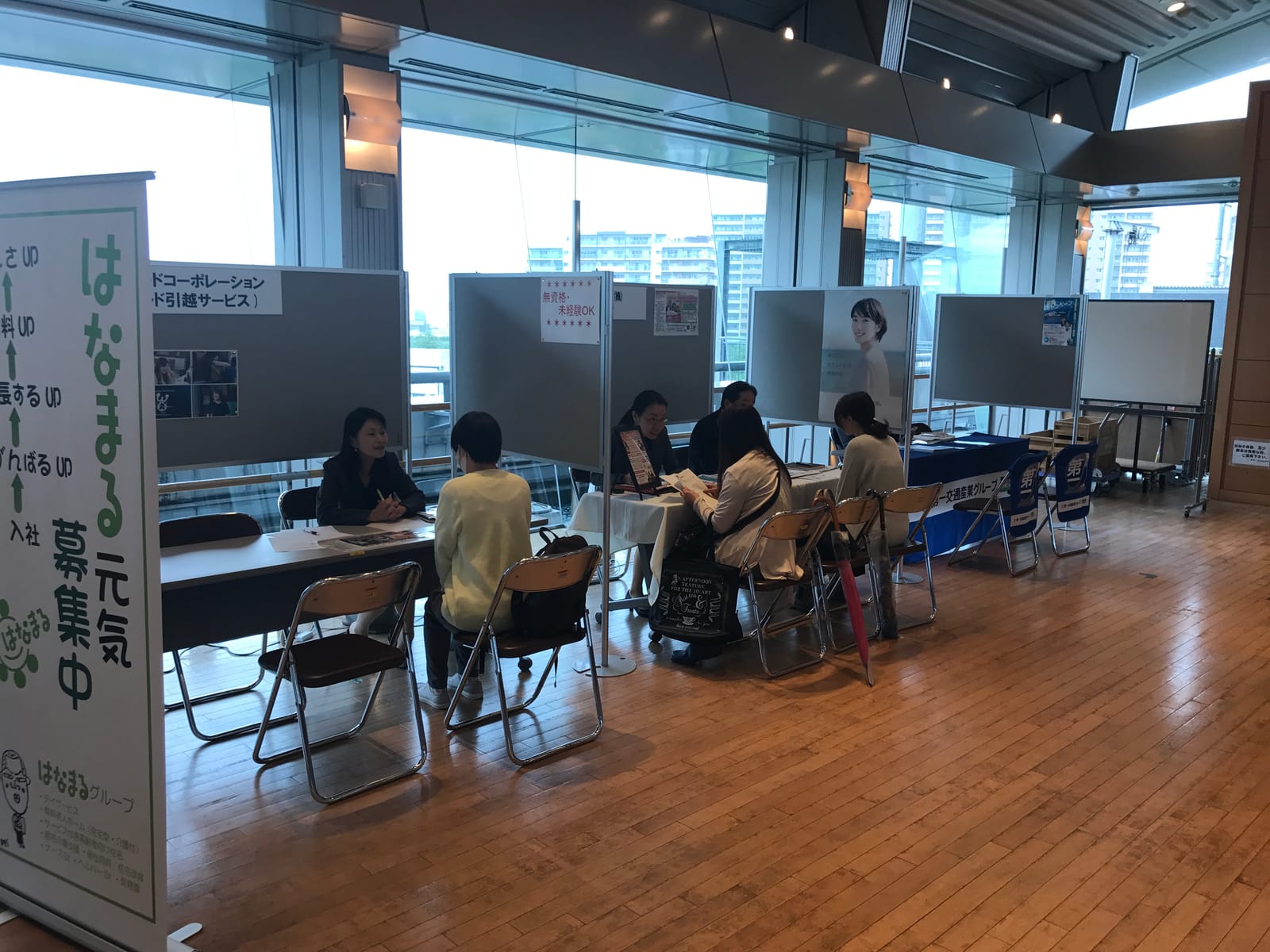 合同就職説明会の会場。窓際に企業ブースが並び、来場者が採用担当者と面談している