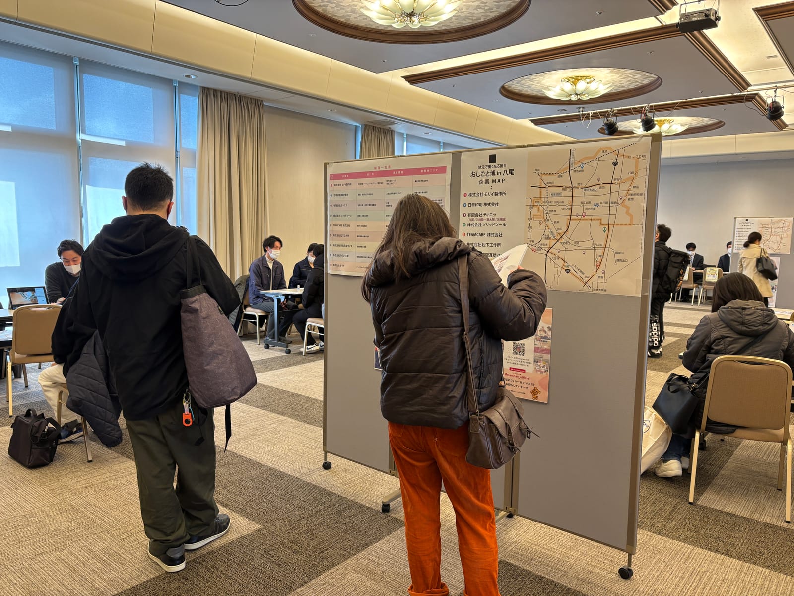会場のパネルに貼られた企業MAPと職種一覧を、来場者が見ている